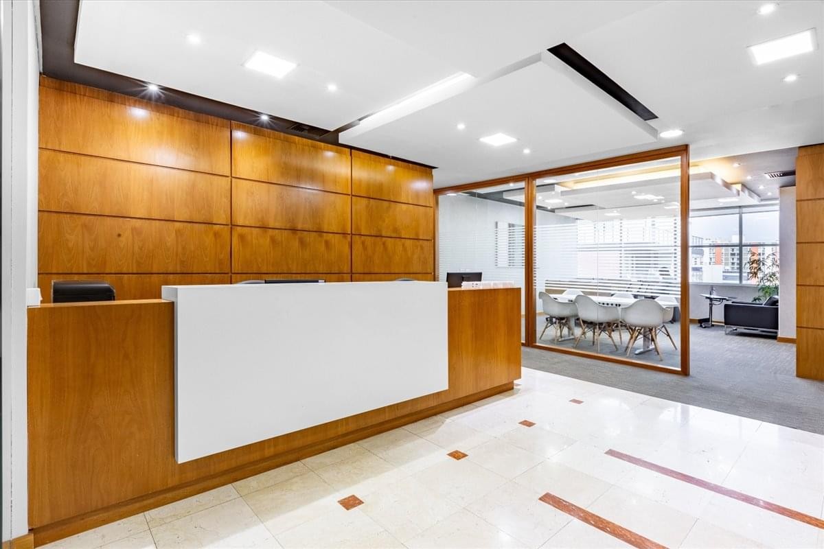 Bright reception area at 499 Comendador Araujo Street (10th Floor), Curitiba, Brazil with wood paneling and a white desk.