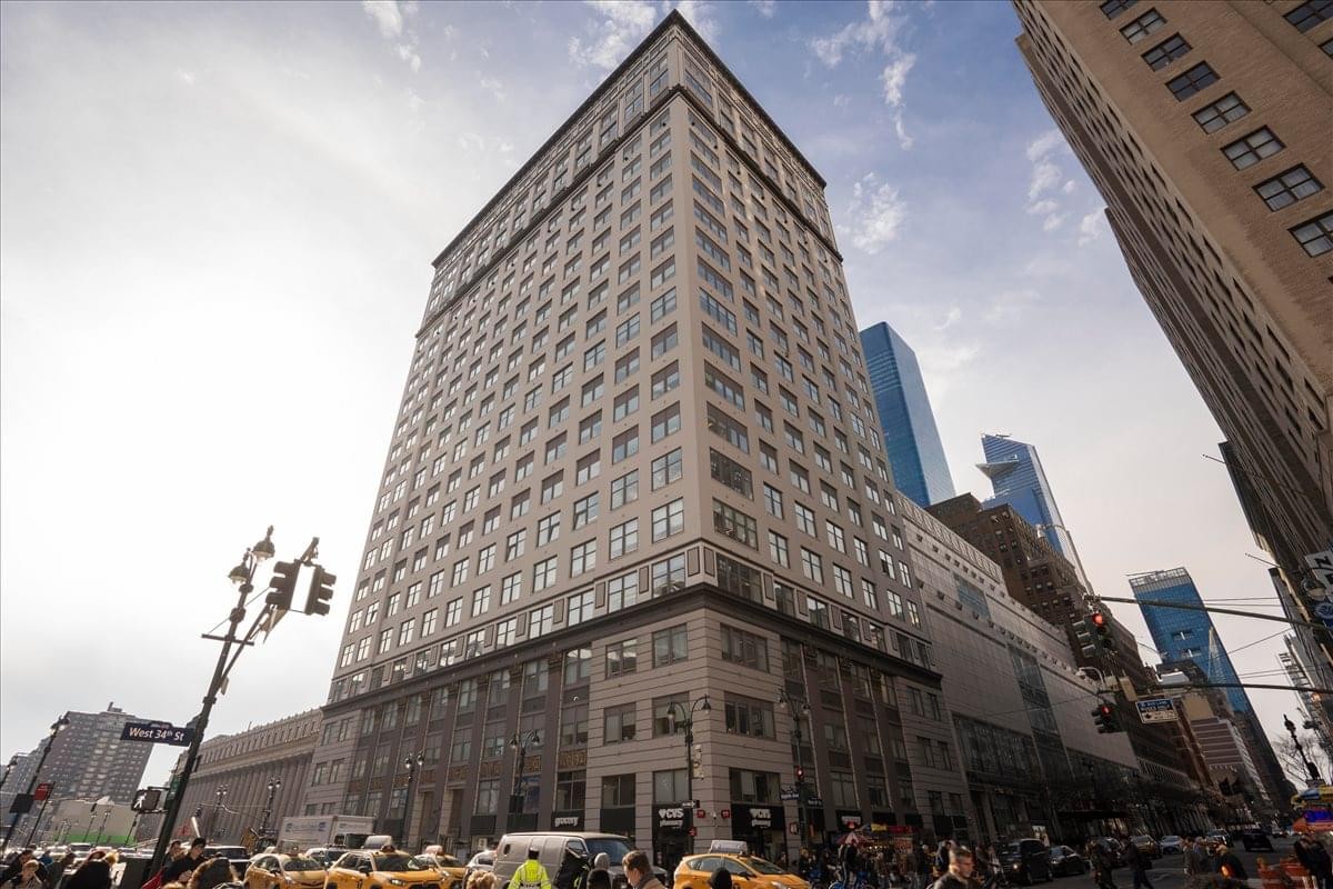 Exterior view of the historic 5 Penn Plaza high-rise building against a blue sky.