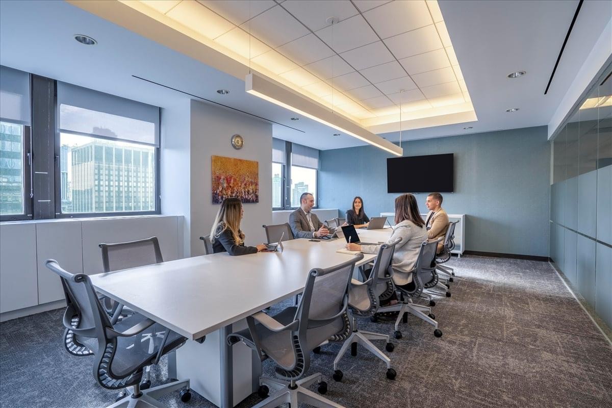 Spacious boardroom with a long white table and linear pendant lighting.