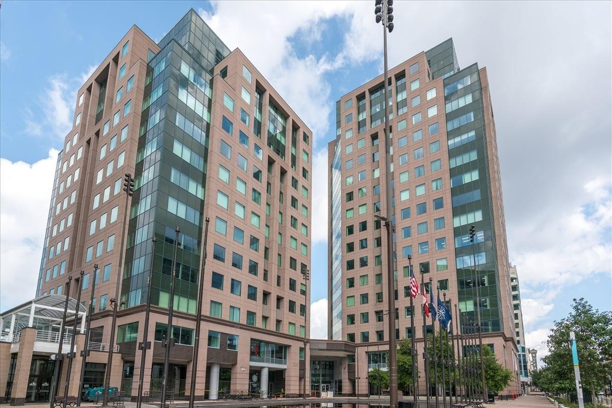 The glass and brick twin towers of 50 Fountain Plaza under a bright blue sky.
