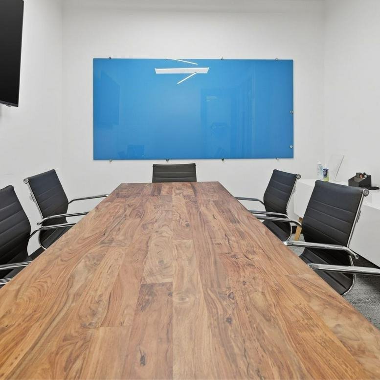 Modern meeting room at 501 Union Street, Suite 400, featuring a large wood table and blue glass whiteboard.