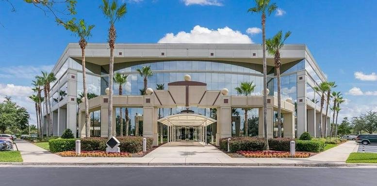 Symmetrical exterior view of the glass-facade 5011 Gate Parkway Building 100 center with palm trees.