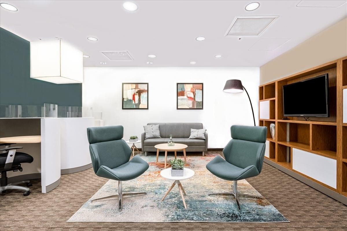 Modern lounge area featuring blue armchairs, a patterned rug, and built-in shelving.