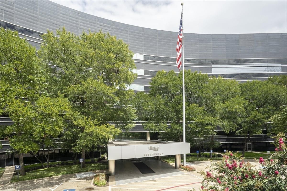 Exterior facade and entrance of the curved glass building at 5050 Quorum Drive.