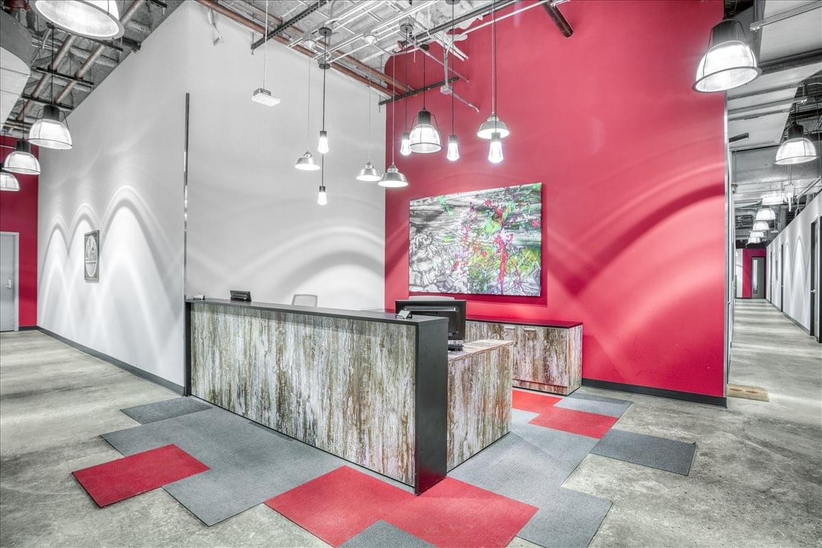 Professional reception desk with a vibrant red feature wall and stylish patterned flooring.