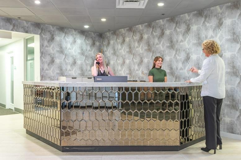 Lobby at 515 North Flagler Drive, Suite 300, showing a textured wall and golden patterned reception desk.
