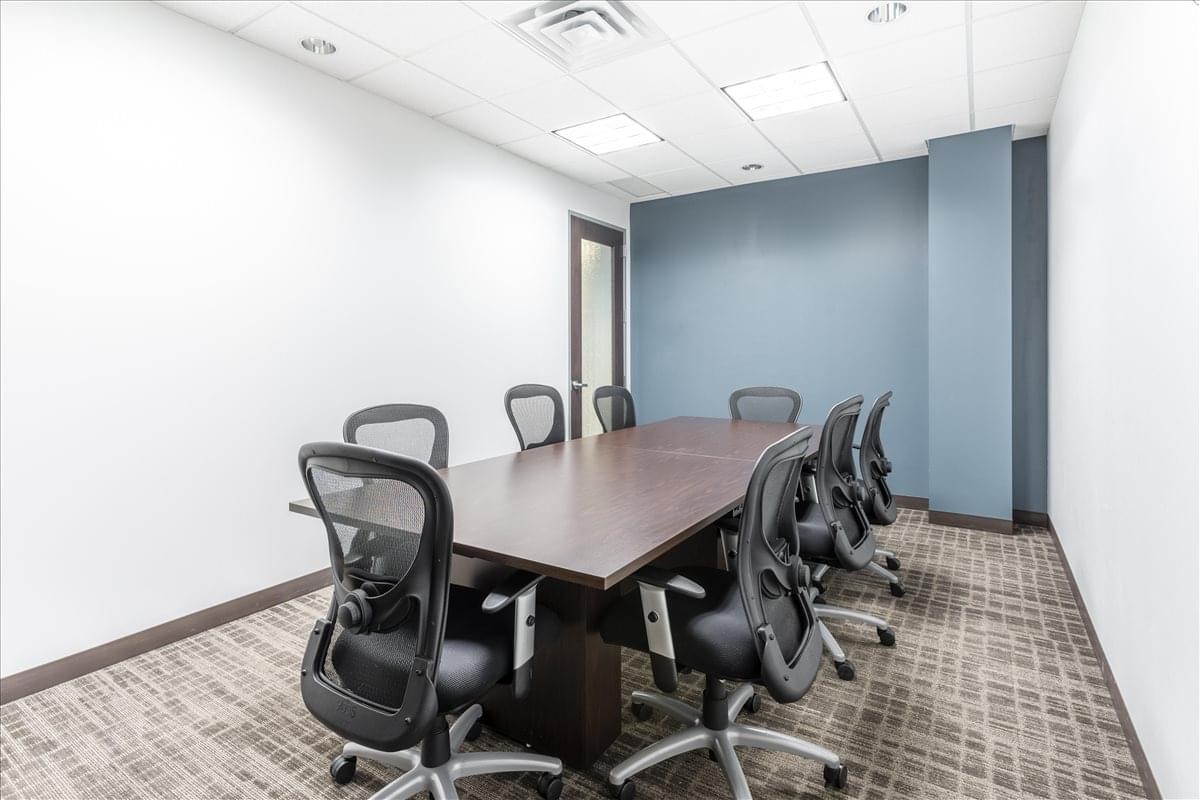 Meeting room at The Edina Grandview Center featuring a dark wood table and blue feature wall.