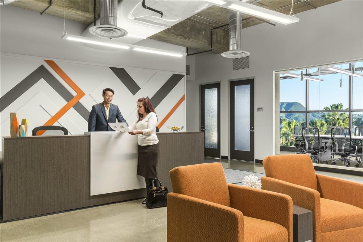 Modern reception area at 5250 N. Lankershim Blvd, Suite 550, with orange armchairs and a geometric wall mural.