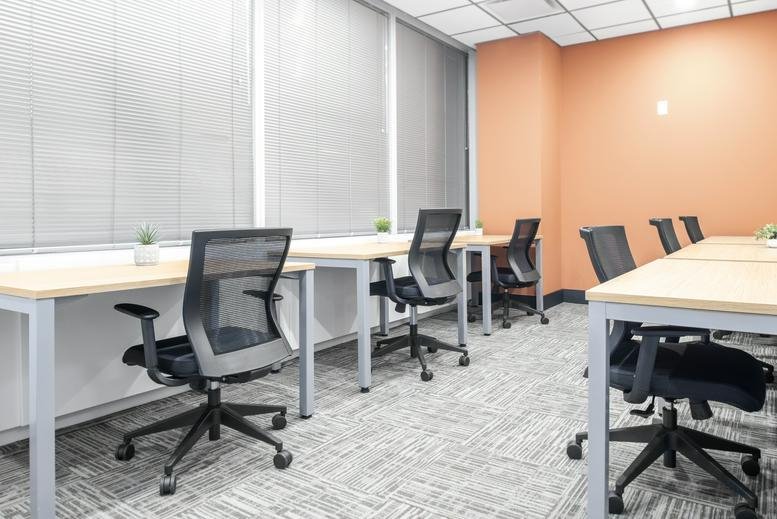 Open-plan workspace with multiple desks and an orange feature wall at Venture X North York, 5255 Yonge Street.