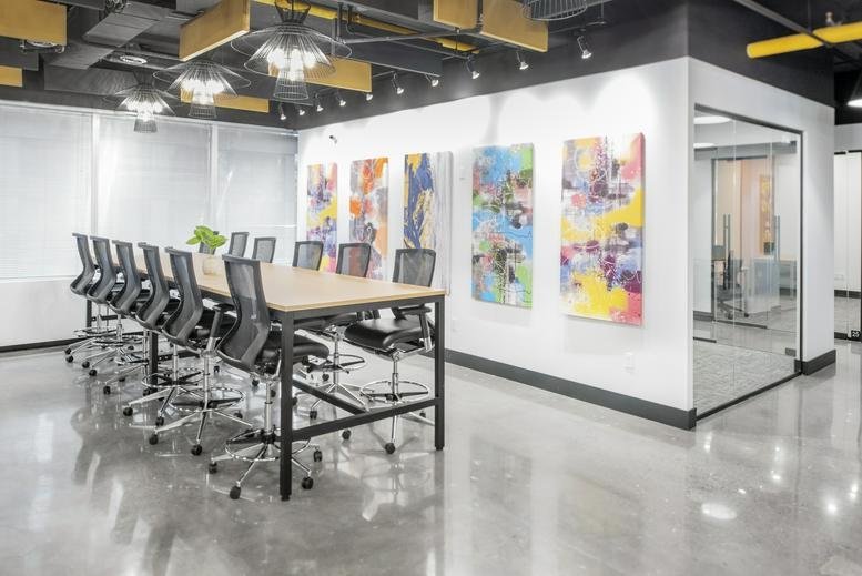 Spacious communal area at Venture X North York, 5255 Yonge Street with a large wooden table and colorful art.