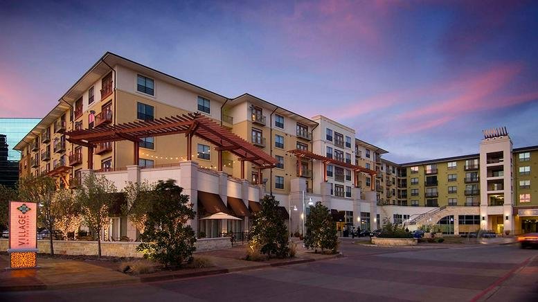 Exterior view of the multi-story modern residential and commercial building at 5301 Alpha Rd. E80.