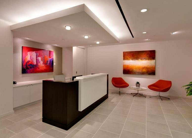 Professional reception area with a dark wood desk, warm lighting, and vibrant abstract artwork.