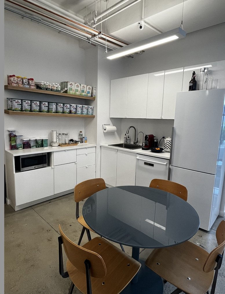 Bright communal kitchen and dining area with a round grey table and wooden chairs at 535 8th Avenue.