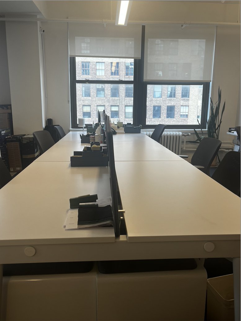 Bright open-plan workspace at 535 8th Avenue with long white desks and large windows.