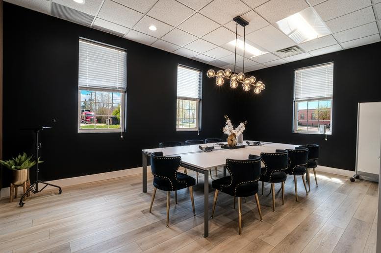 Meeting room at Brick House Co-Working with black walls, white table, and globe chandelier.