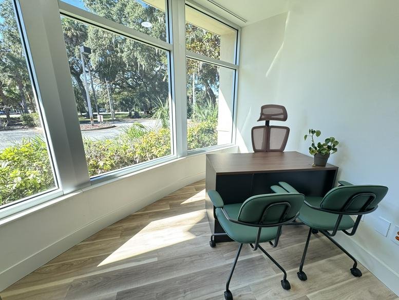 Private office at The Canopy, North Oceanshore Boulevard featuring a window view and green accent chairs.