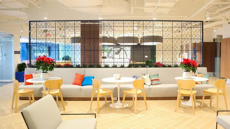 Spacious communal lounge at 5425 Wisconsin Avenue, Suite 600 with colorful pillows and floral arrangements.