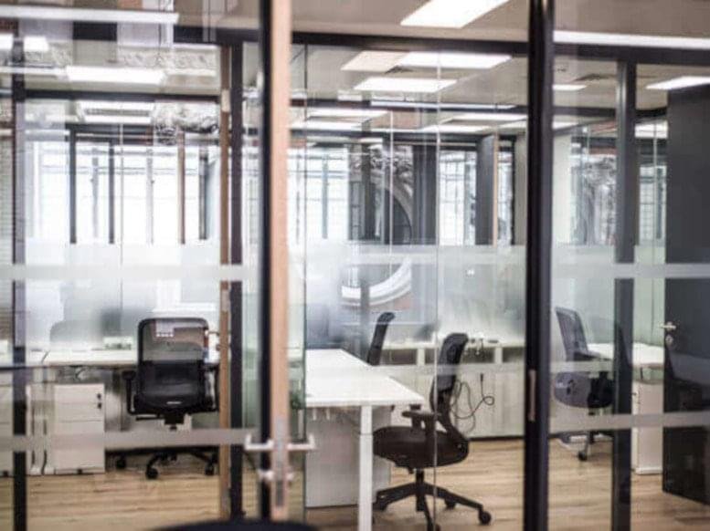 Bright glass-walled office suites at 555 Anton Boulevard Costa Mesa, California featuring ergonomic chairs.