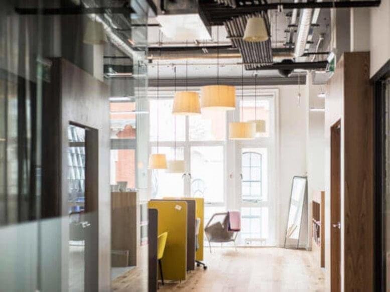 Bright corridor at 555 Anton Boulevard featuring hanging pendant lights and yellow divider screens.