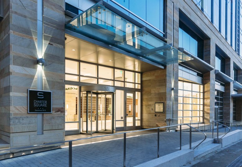 Glass-canopied main entrance to Charter Square featuring a revolving door and stone facade.