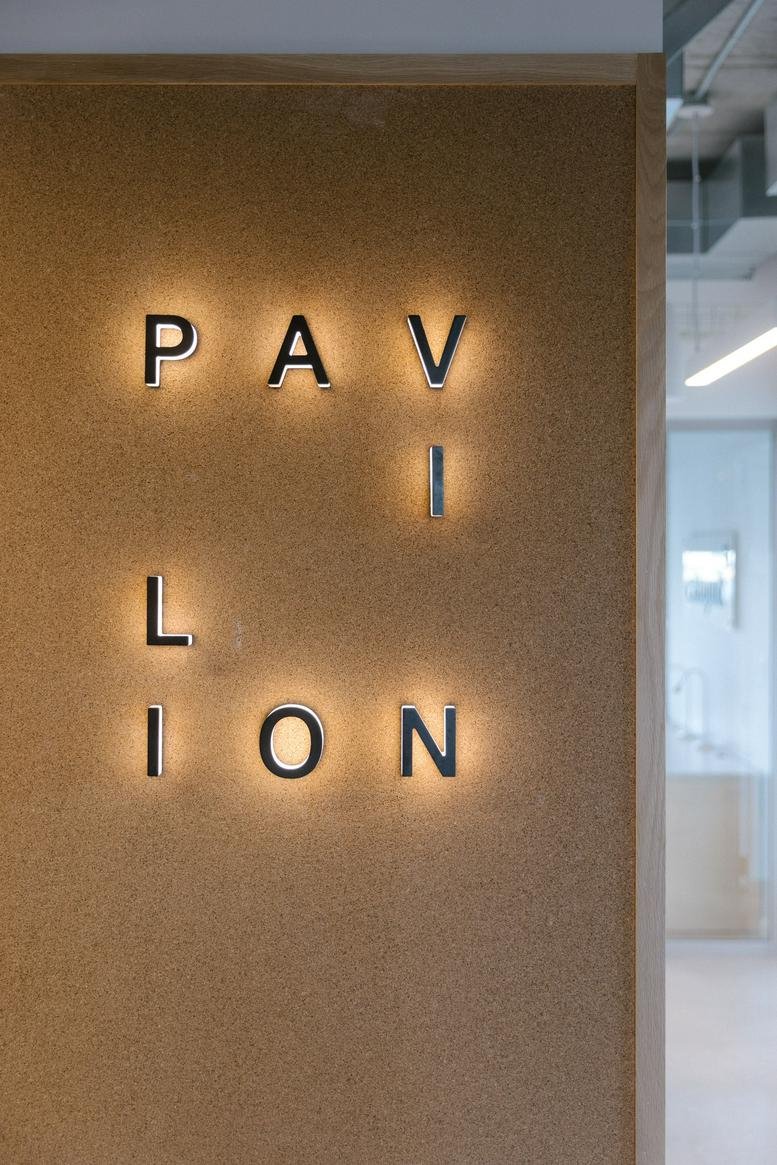 A textured wall featuring the Pavilion Stadium Beatty building name in backlit metal lettering.