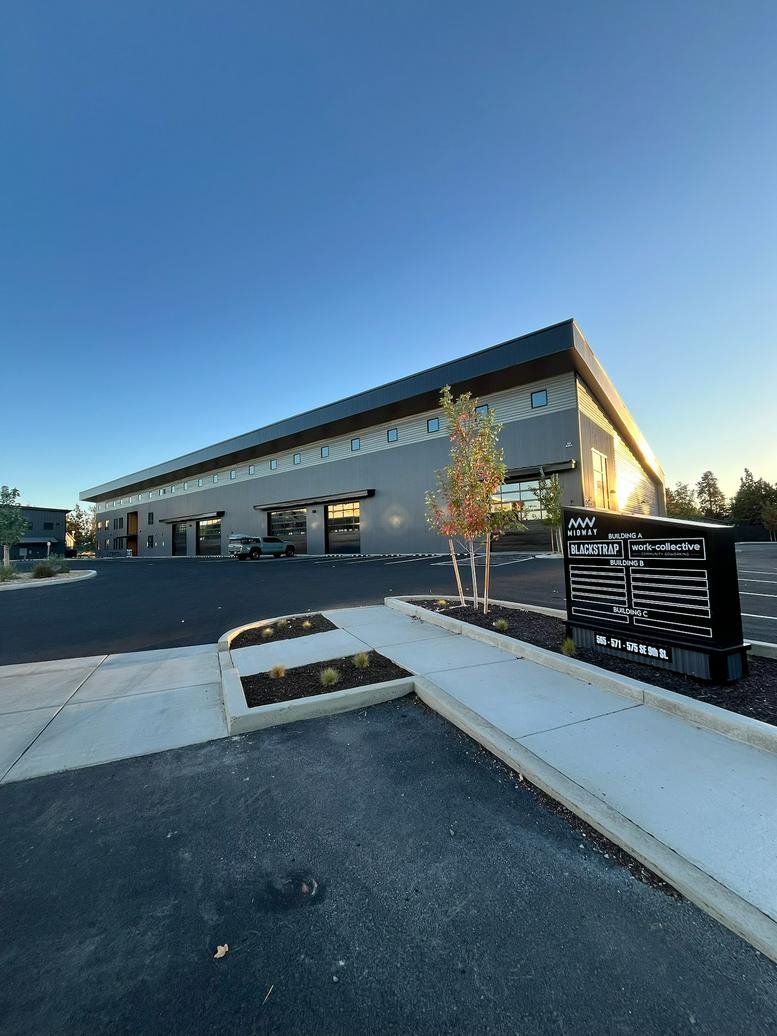 Exterior view of the contemporary Work-Collective Midway building with grey siding and large windows.