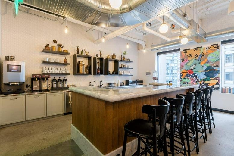 Cafe area at 575 Market St featuring a marble bar, coffee machine, and colorful abstract wall art.