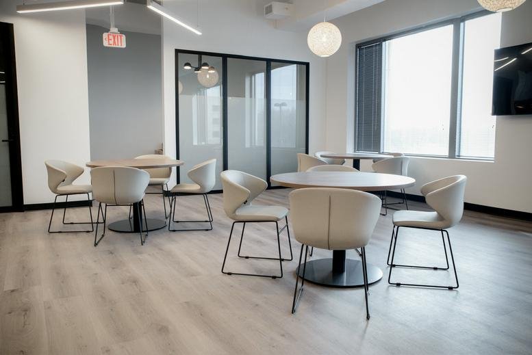 Spacious communal lounge with modern armchairs and round cafe tables.