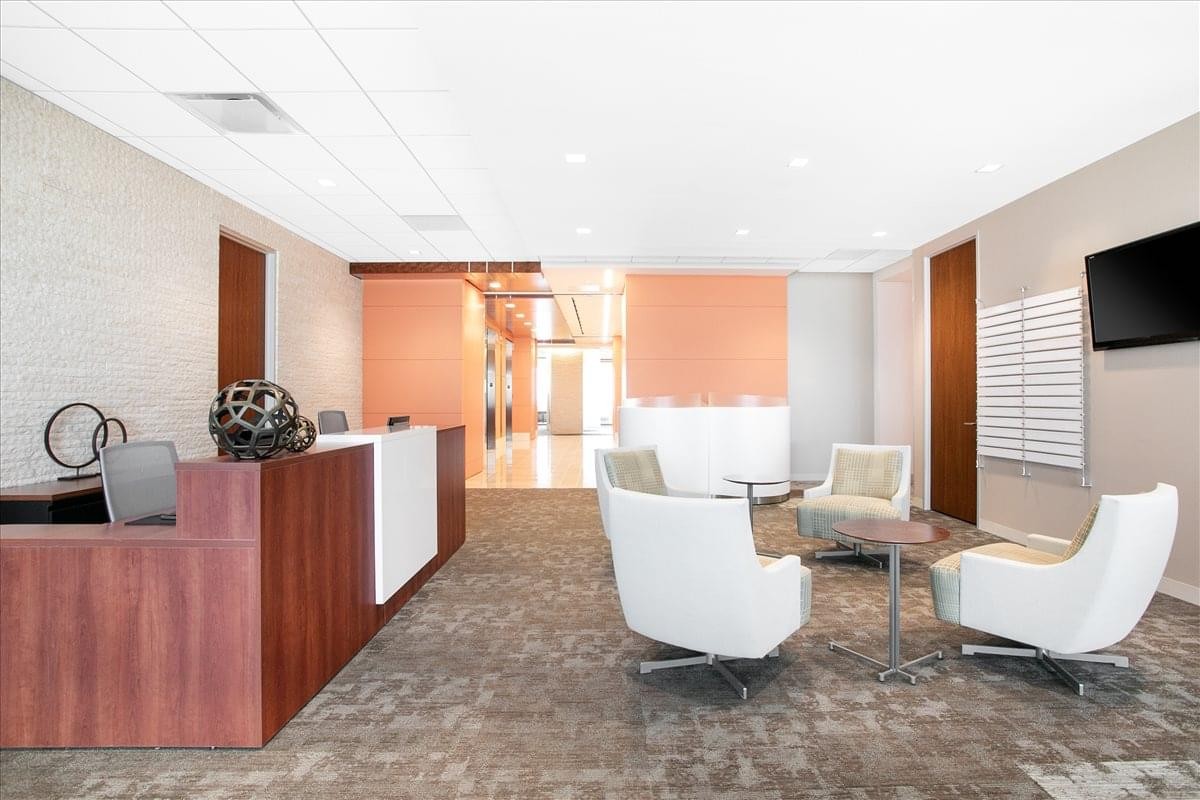 Spacious reception area at 5851 Legacy Circle, 6th Floor with warm wood accents and white lounge chairs.