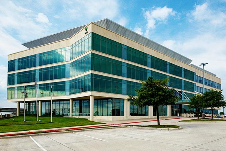 Exterior view of the glass-facade Valliance Plaza building with green lawns.