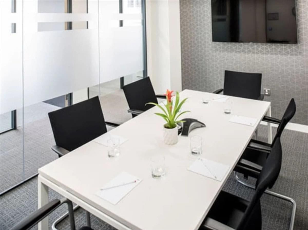 A professional meeting room at 5940 Macleod Trail SW, Suite 500 with a white table and black chairs.