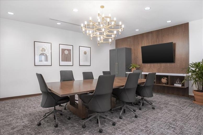 Boardroom featuring a large wood table, chandelier, and framed artwork.