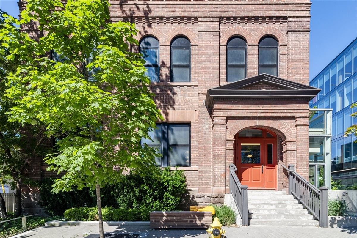 Red brick exterior of 60 Atlantic Avenue featuring arched windows and a bright orange door.