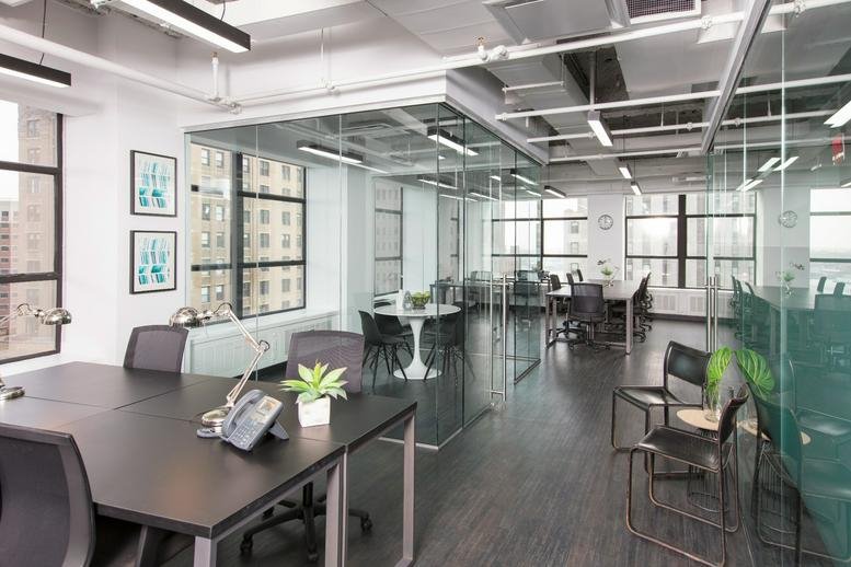Modern workspace with black desks and glass office partitions.