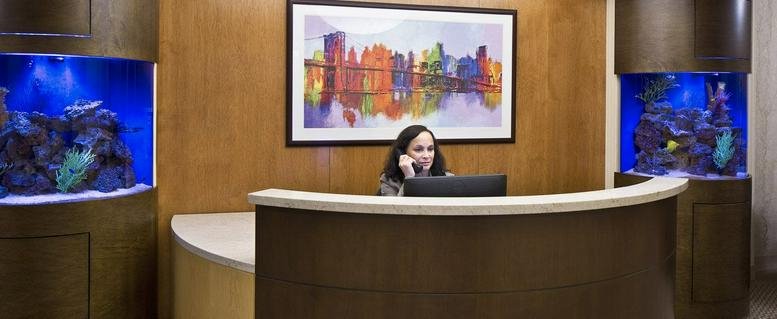 Wooden reception desk flanked by two large vibrant saltwater aquariums.