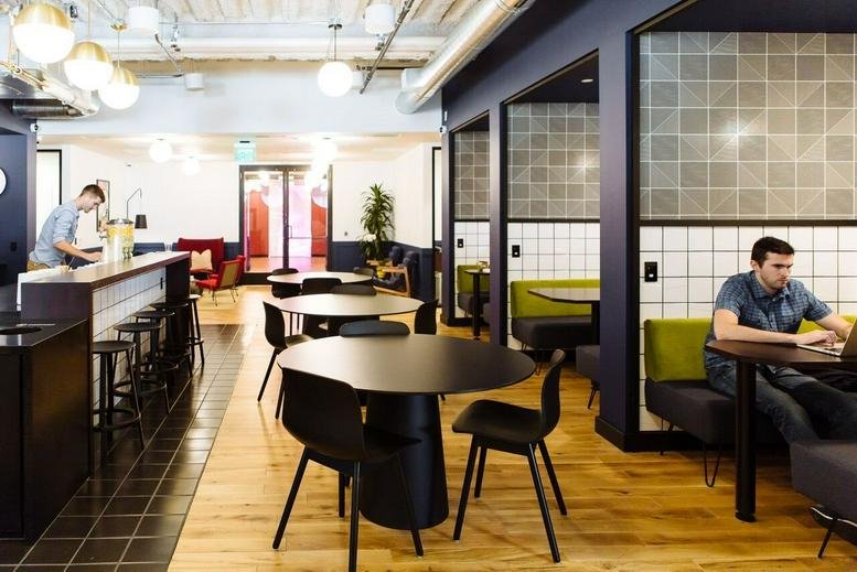 A vibrant cafe-style communal space at 600 California Street with round tables and private booths.