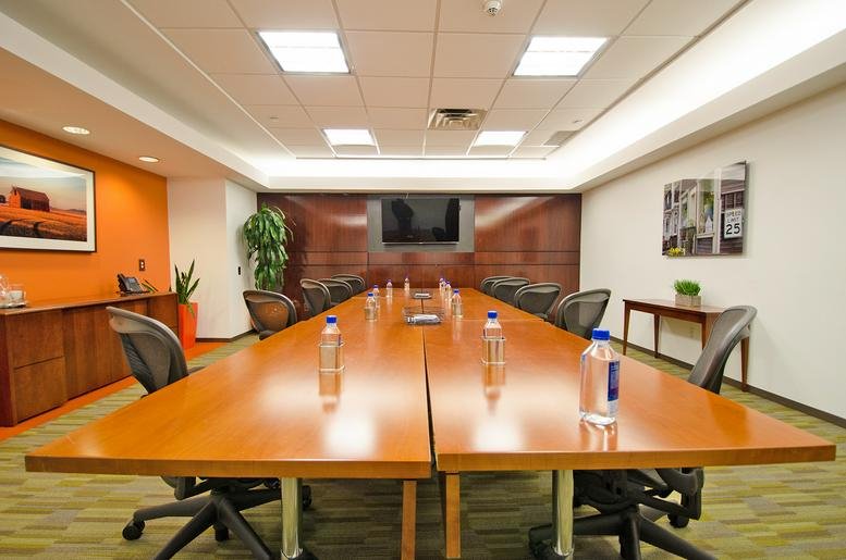 Large boardroom at 600 Mamaroneck Avenue, Suite 400 with long wood table and orange feature wall.