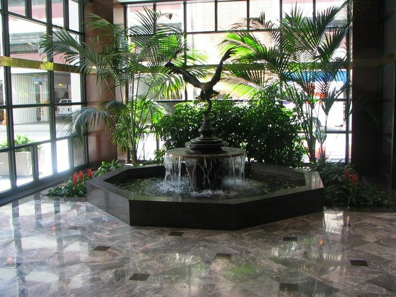 Lobby at 600 Republic Centre featuring a black stone fountain with an eagle statue surrounded by indoor palm trees.