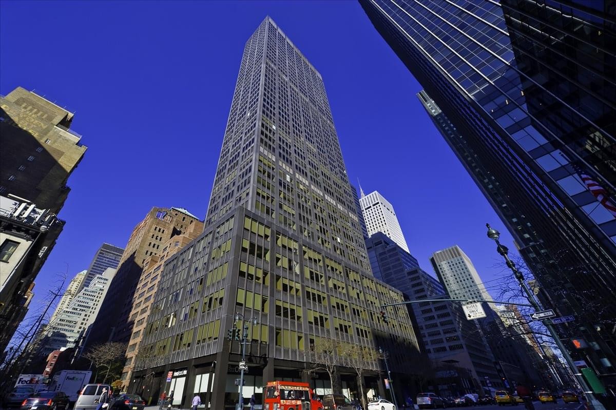 Low-angle exterior view of the towering 600 Third Avenue skyscraper against a deep blue sky.