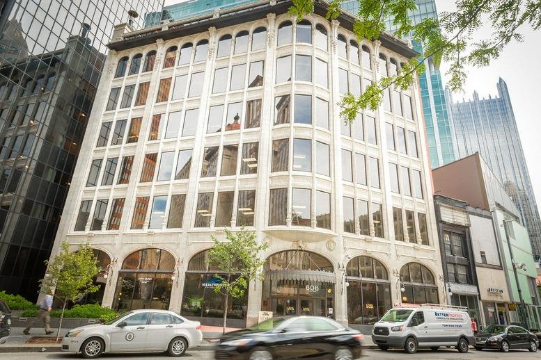Exterior view of the historic white facade of 606 Liberty Avenue with arched ground-floor windows.