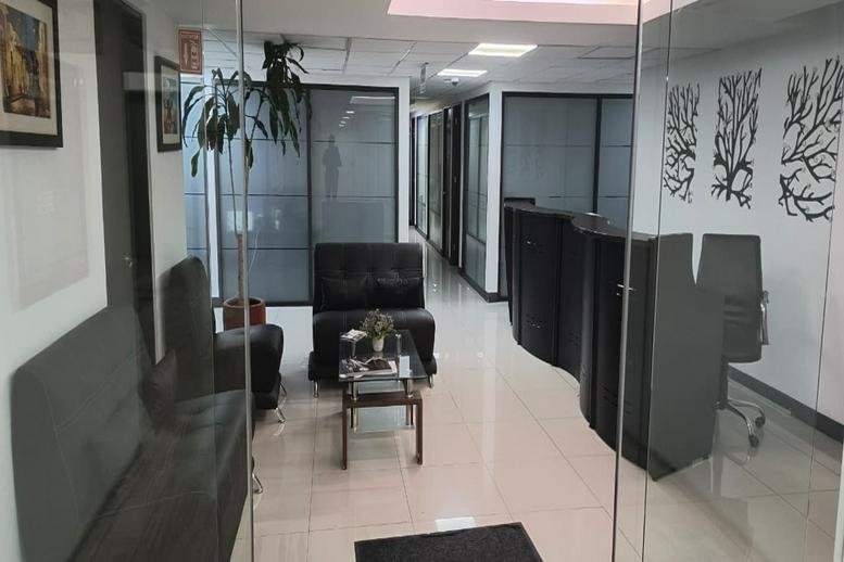 Reception and waiting area at 61 Bosque de Duraznos, Piso 3 (CNB), featuring dark armchairs and potted plants.