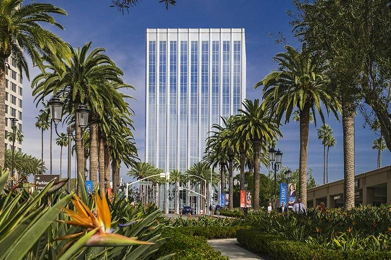 Exterior view of the white high-rise building at 620 Newport Center Drive surrounded by palm trees.