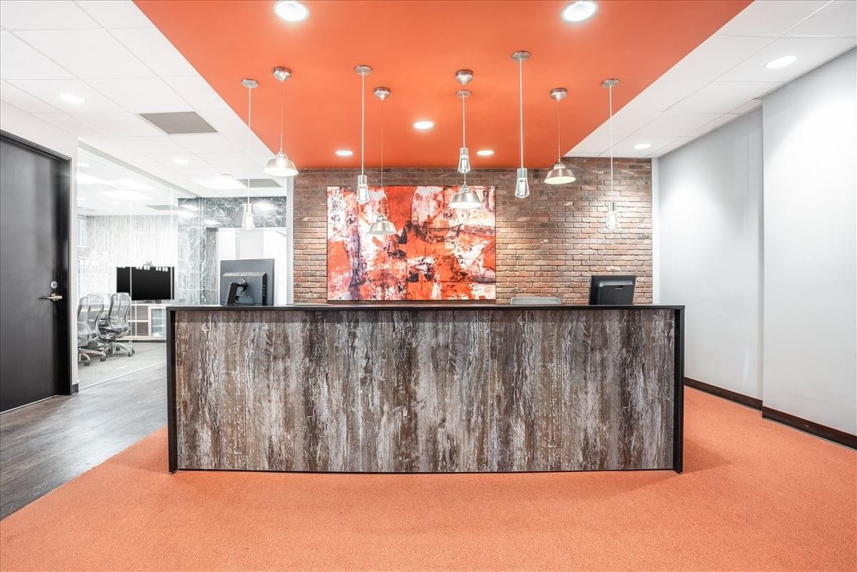 Modern reception desk with wood-paneling and a vibrant orange ceiling.