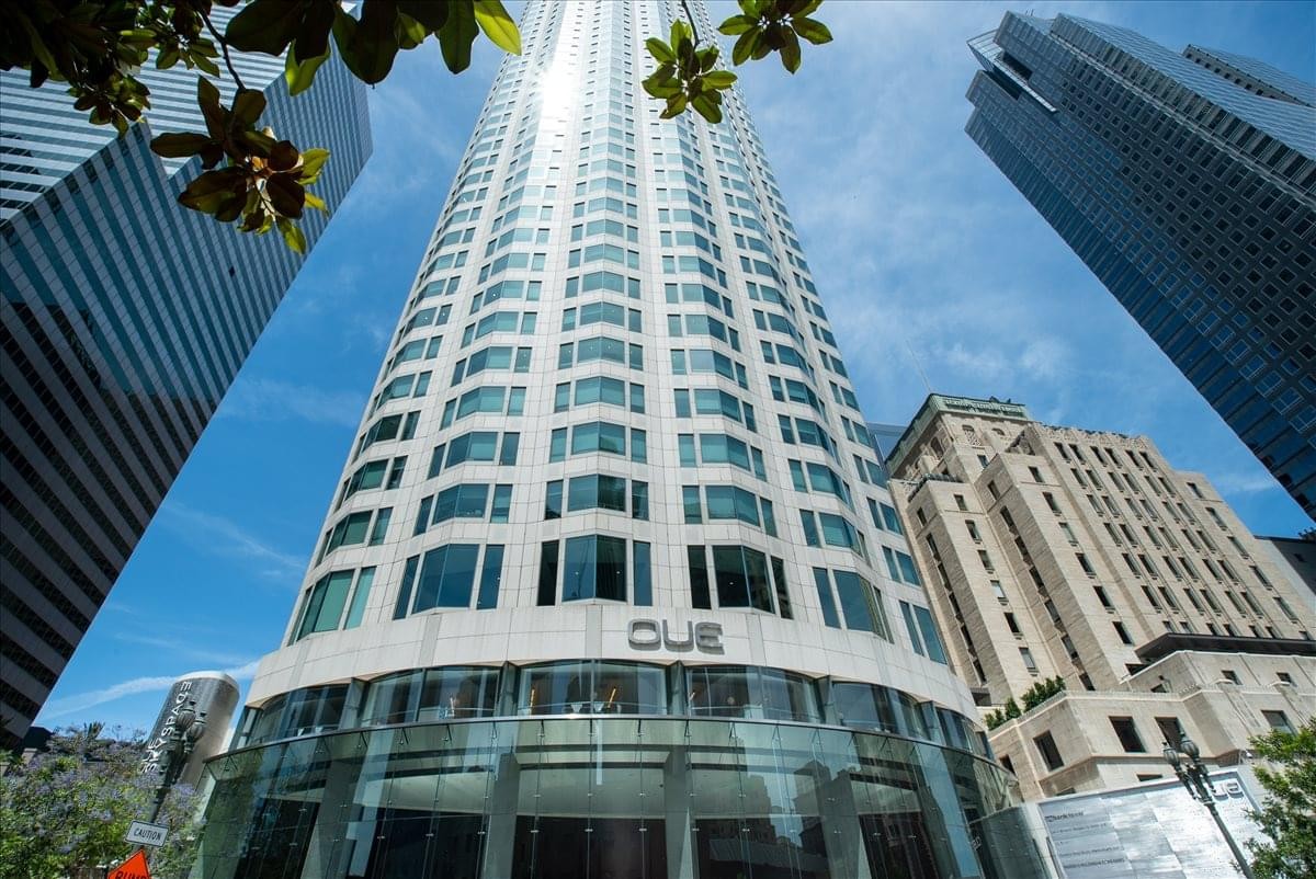 Exterior view of the tall, curved glass facade of the U. S. Bank Tower under a bright blue sky.