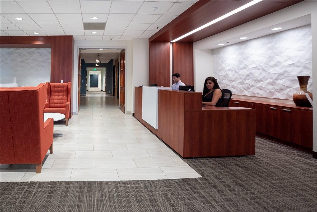 Elegant reception area of the US Bank Tower, 28th Floor, featuring a dark wood desk and red lounge seating.