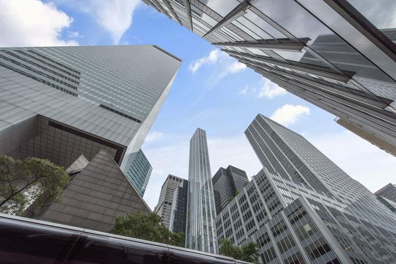 Looking up at the modern glass skyscraper facade of 641 Lexington Avenue against a blue sky.