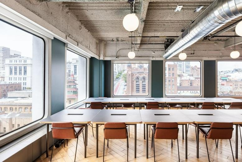 Spacious coworking area at 650 California Street featuring long tables, leather chairs and city views.