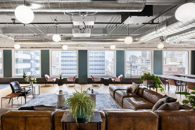 Spacious communal lounge with leather sofas, potted plants, and exposed ceilings.