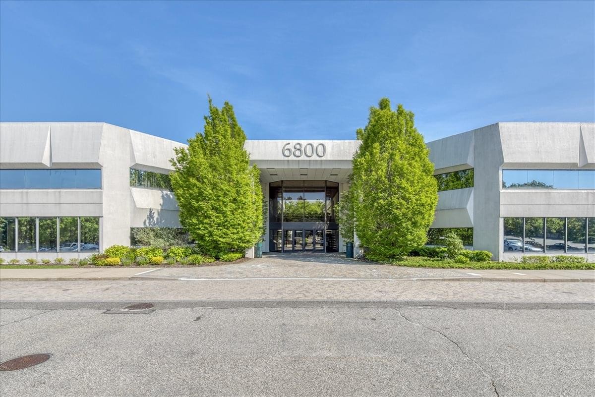 Symmetric exterior facade of the 6800 Jericho Turnpike building with green landscaping and a glass entrance.