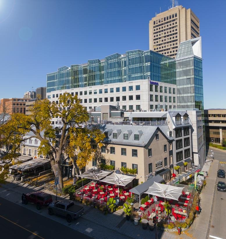 Exterior view of the tiered facade at Espace Grande Allée with outdoor restaurant seating.